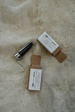 Two small boxes of bamboo dental floss with labels on a textured beige surface