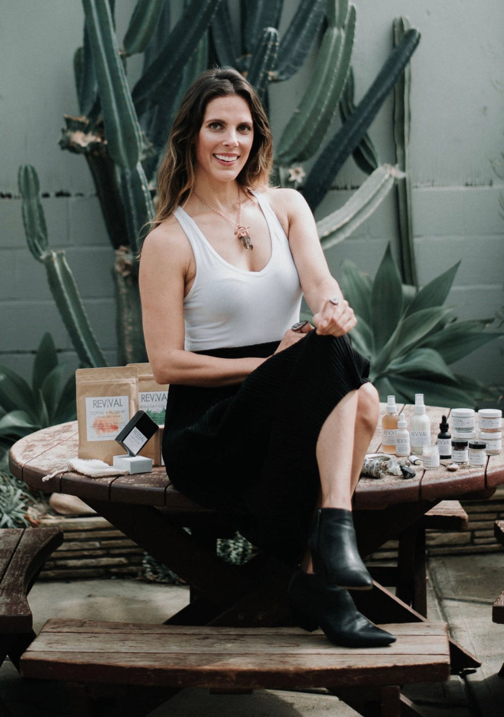 Woman sitting on a wooden table with products and cacti in the background