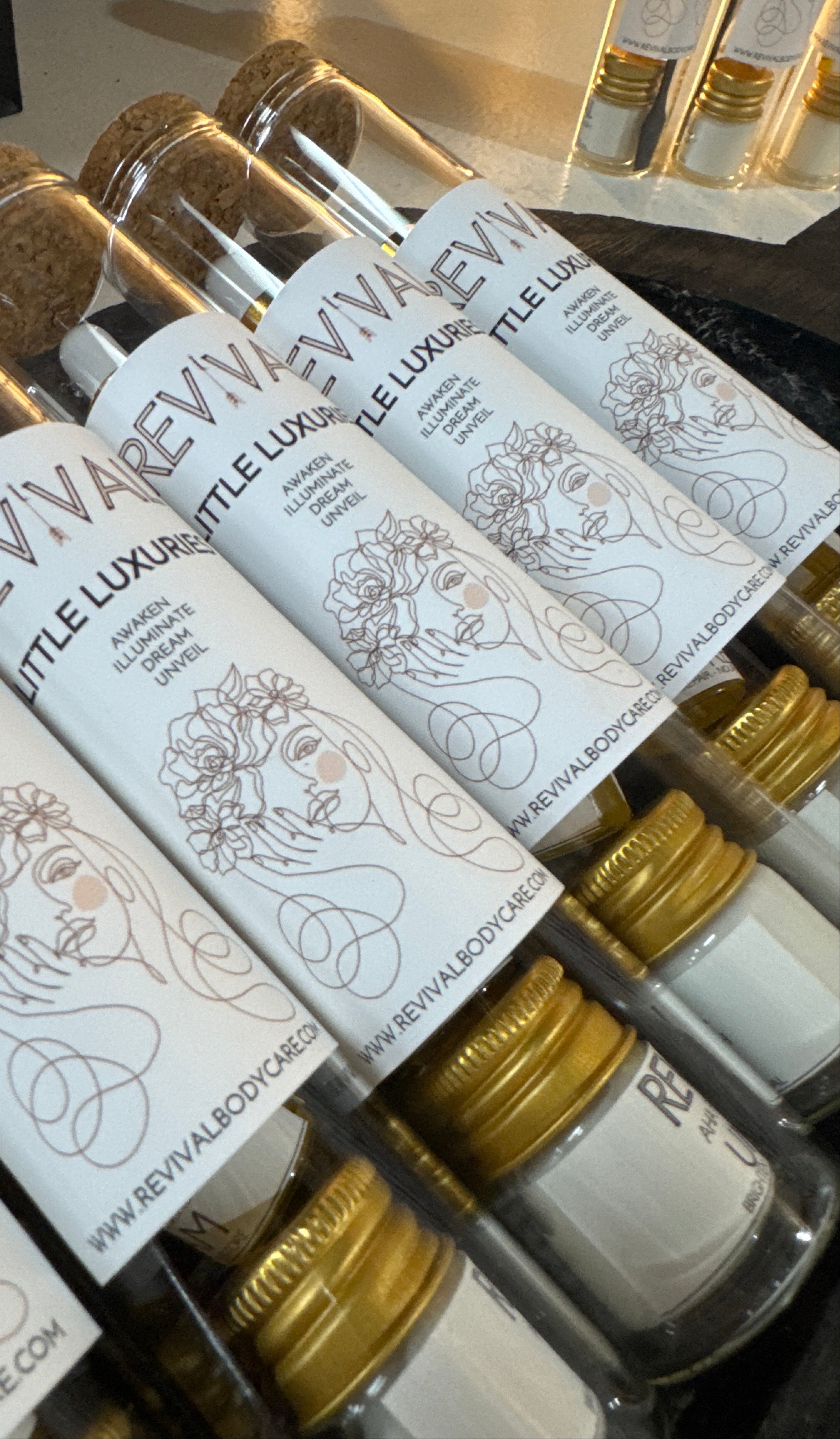Row of small bottles with gold caps and white labels on a black background