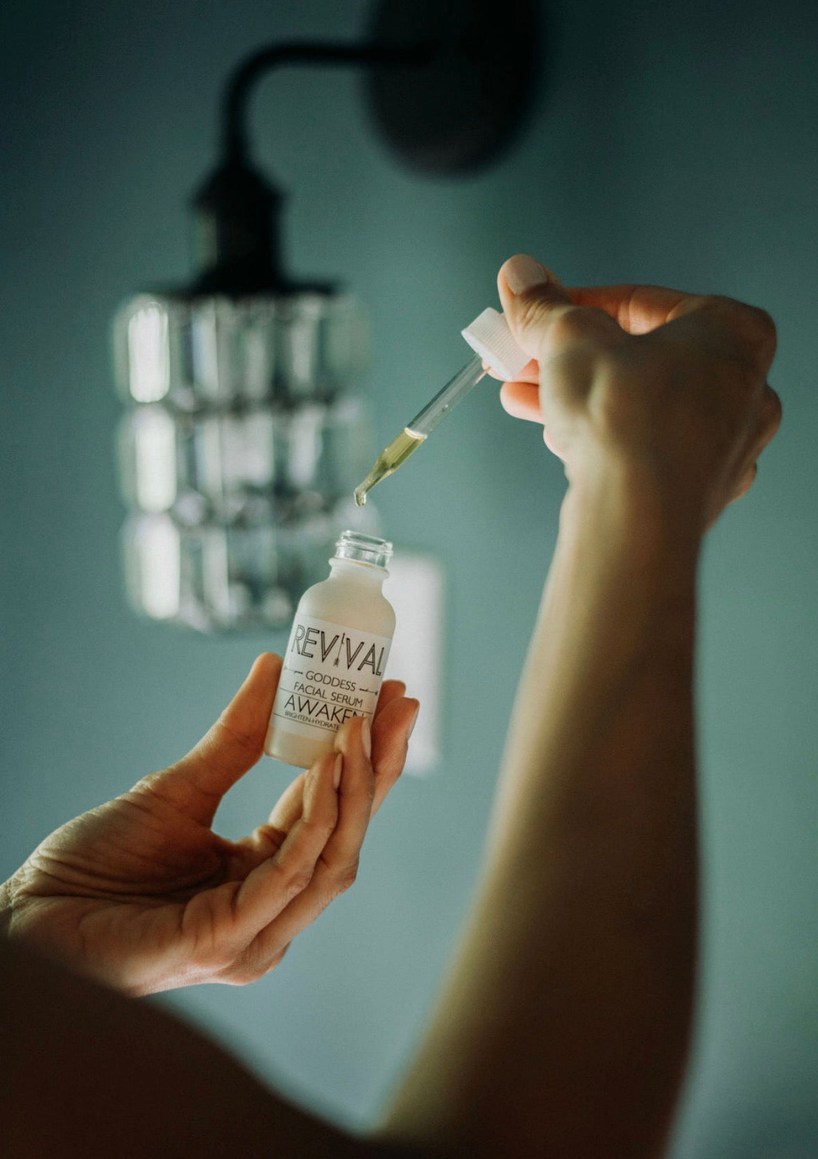 Person holding a Revival Awaken bottle with a dropper against a blurred background