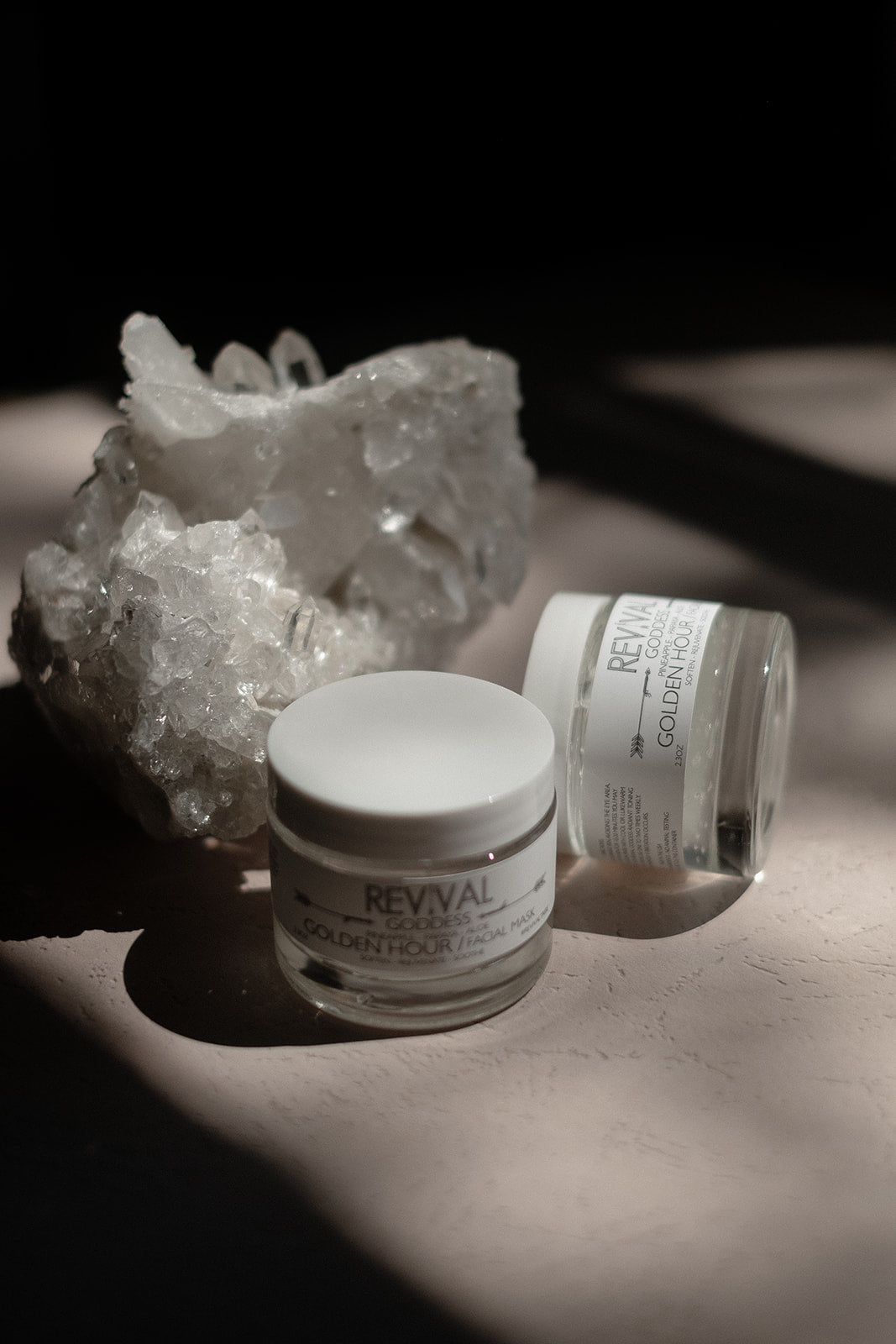 Two jars labeled 'Revival' Golden Hour on a textured surface with a crystal formation in the background.