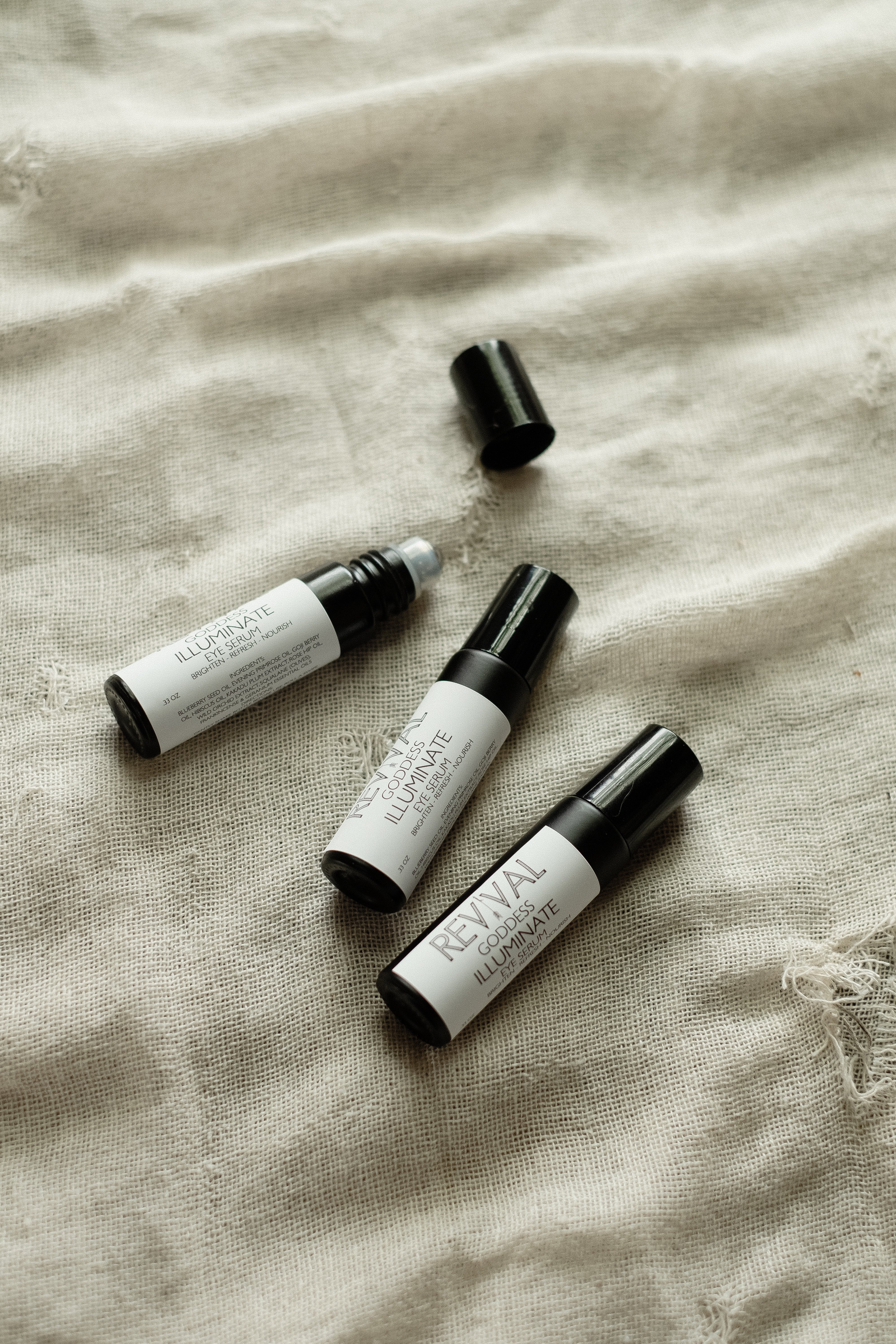 Three small bottles with labels on a textured beige fabric background