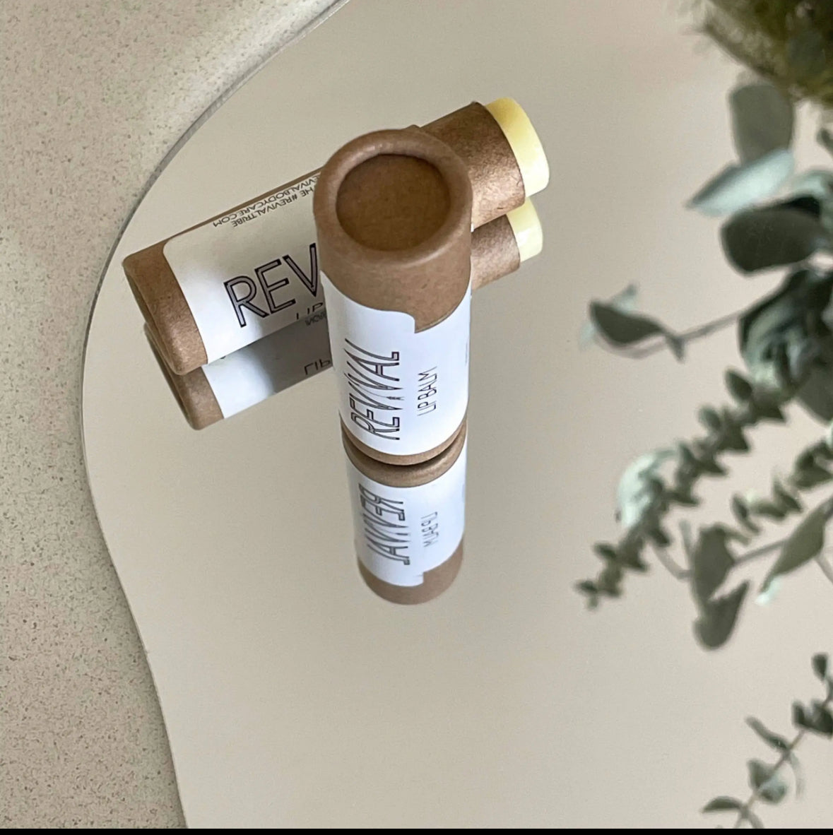 A stick of lip balm with the brand name 'REVIVAL' placed on a surface, partially used.