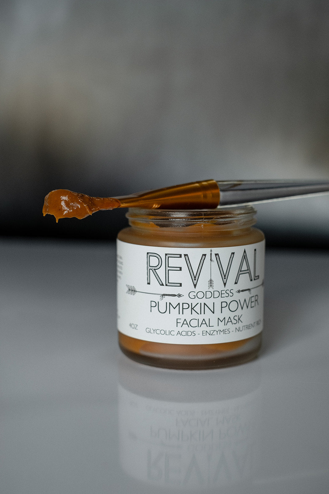 Jar of Revival Goddess Pumpkin Power Facial Mask with a applicator on a gray background