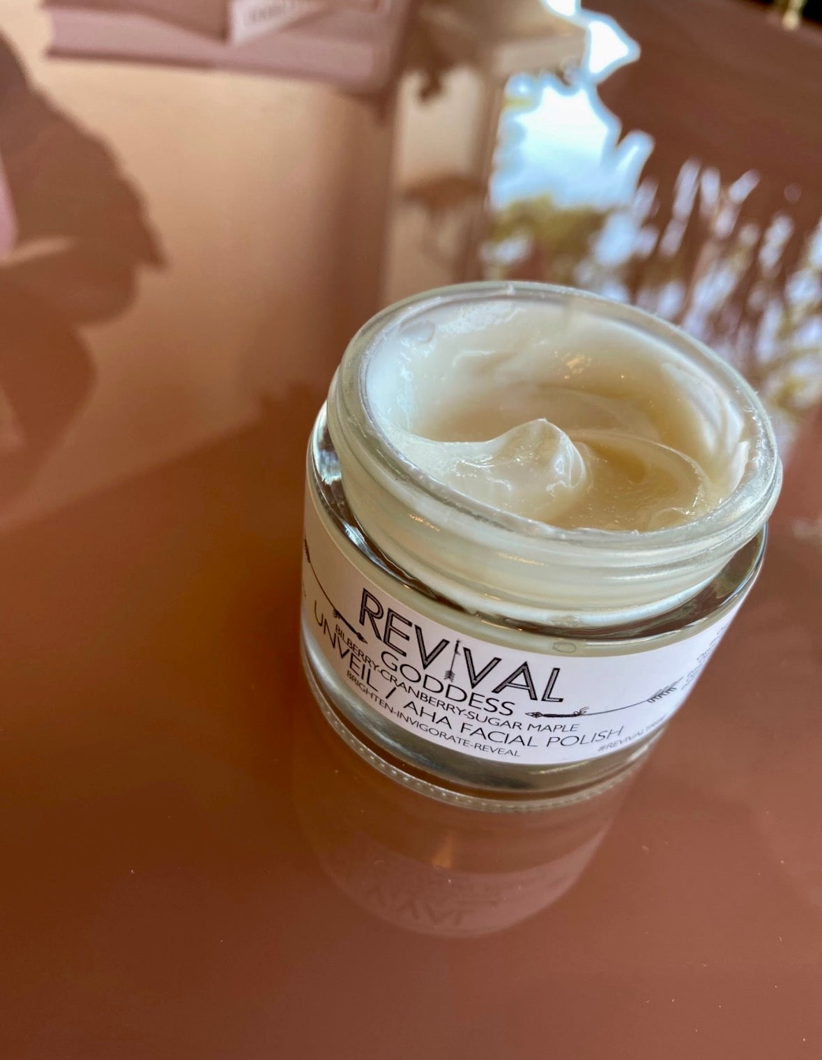Jar of cream with 'Revival' label on a reflective surface