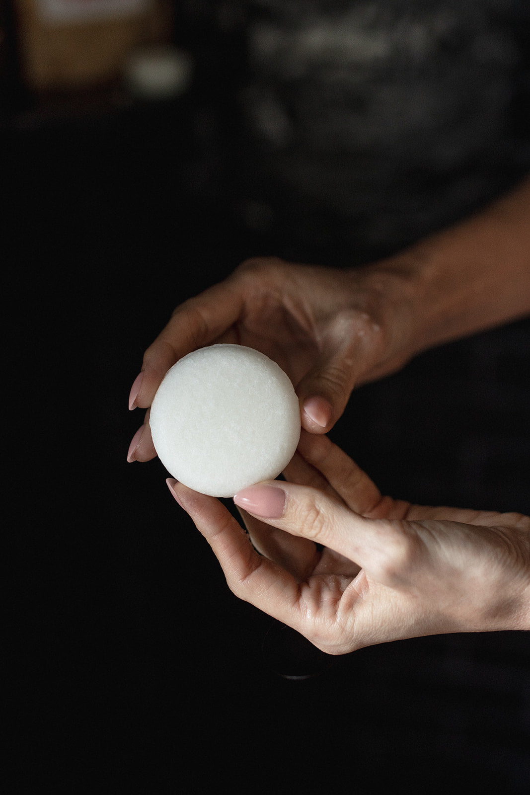 Hand holding a shampoo bar against a dark background