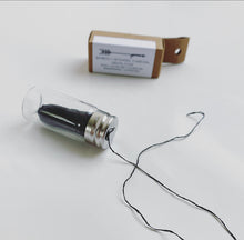 dental floss pulled out of a glass bottle 